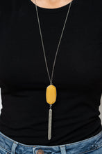 Load image into Gallery viewer, Featuring a faceted surface, a dewy yellow acrylic gem swings from the bottom of a lengthened silver chain. A shimmery silver chain tassel attaches to the bottom of the colorful pendant, adding flirtatious movement. Features an adjustable clasp closure.