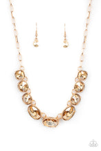 Load image into Gallery viewer, Featuring mismatched round, oval, and square cuts, a golden row of dramatically oversized rhinestones delicately link below the collar for an icy finish. Features an adjustable clasp closure. Sold as one individual necklace. Includes one pair of matching earrings.