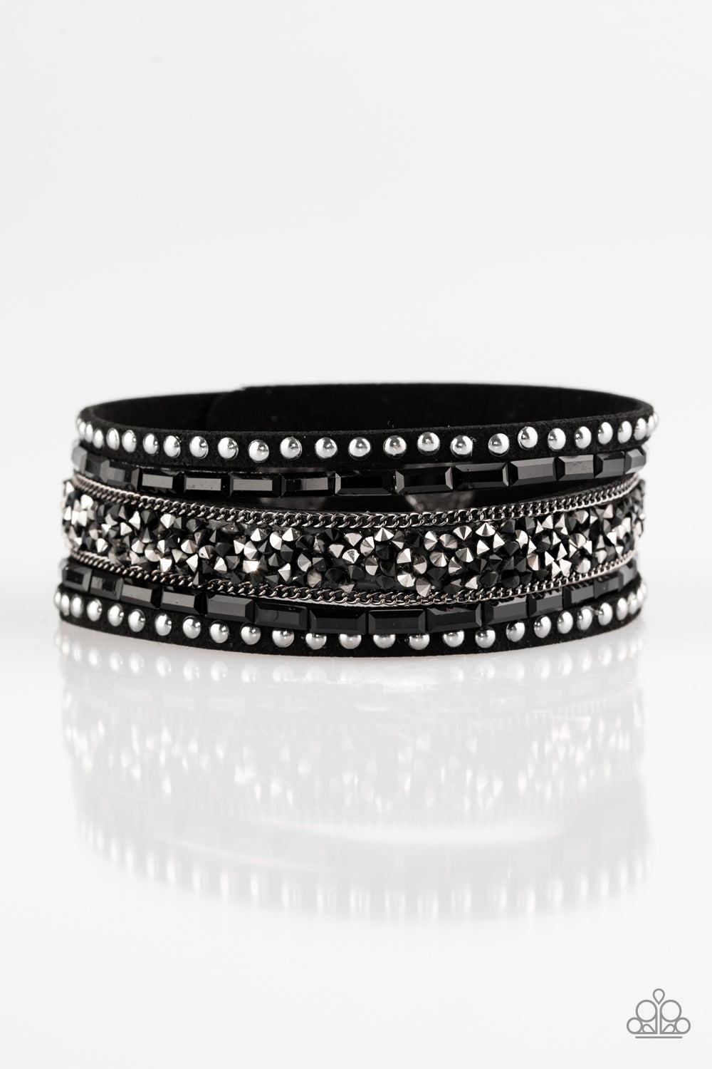 Featuring edgy emerald and prism style cuts, black and hematite rhinestones are encrusted down the center of a black suede band that has been spliced into three. Shiny gunmetal studs and glistening gunmetal chains are added for a sassy industrial finish. Features an adjustable snap closure.