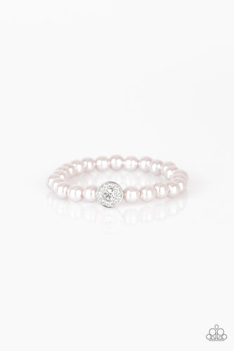 Silver pearls and a white rhinestone encrusted silver charm are threaded along a stretchy band, creating a glamorous centerpiece atop the wrist.