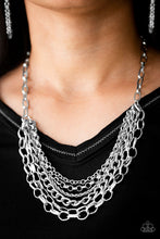 Load image into Gallery viewer, Mismatched silver chains layer below the collar for a bold industrial look. Painted in a neutral finish, a shiny gray chain drapes between the shimmery silver chains for a vivacious finish. Features an adjustable clasp closure.  Sold as one individual necklace by Paparazzi. Includes one pair of matching earrings.
