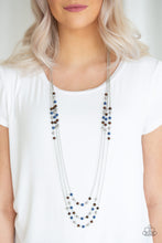 Load image into Gallery viewer, Dainty silver, blue, and wooden beads trickle along three shimmery silver chains, creating colorful layers across the chest. Features an adjustable clasp closure.  Sold as one individual necklace. Includes one pair of matching earrings.
