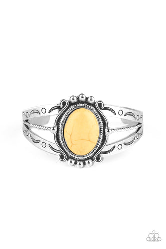 A twisted silver bar is flanked by two silver bands stamped in artisan inspired patterns, coalescing into an airy cuff. Pressed into the center of a decorative silver frame, a sunny yellow stone sits atop the stacked cuff for an earthy finish.
