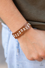 Load image into Gallery viewer, White leather cording is haphazardly laced through the center of a brown leather band, creating a rustic look around the wrist. Features an adjustable snap closure.
