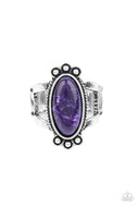An elongated oval purple stone is pressed into the center of a textured silver frame dotted with antiqued silver studs, creating a tranquil centerpiece atop the finger. Features a stretchy band for a flexible fit.