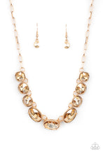 Load image into Gallery viewer, Featuring mismatched round, oval, and square cuts, a golden row of dramatically oversized rhinestones delicately link below the collar for an icy finish. Features an adjustable clasp closure.  Sold as one individual necklace. Includes one pair of matching earrings.
