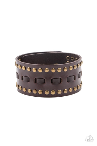 Brown laces are threaded through the center of a brown leather band that has been studded in brass accents, creating a rustic centerpiece around the wrist. Features an adjustable snap closure.