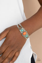 Load image into Gallery viewer, Dotted with a pair of turquoise stone beads, silver floral filigree blooms out from an oval orange stone centerpiece atop a studded silver cuff.

