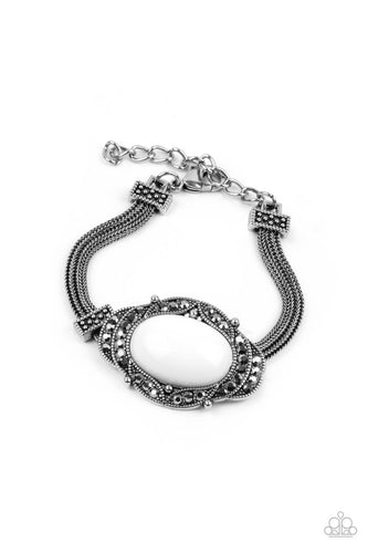 Hematite encrusted silver frames delicately overlap around an oval white bead, creating an edgy centerpiece. The colorful centerpiece attaches to strands of ornate silver chains that are held in place around the wrist by studded silver frames. Features an adjustable clasp closure.