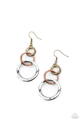 Featuring an antiqued beveled center, warped brass, copper, and silver rings asymmetrically connect into a rustic lure. Earring attaches to a standard fishhook fitting.