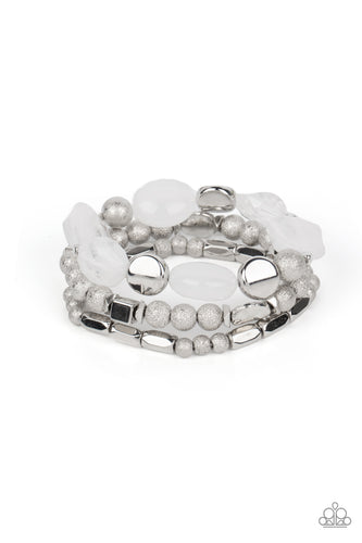 Marina Magic - Paparazzi - Infused with enchanting pops of white crystal-like and glassy accents, a mismatched assortment of hammered, cube, and faceted silver beads are threaded along stretchy bands around the wrist, creating shimmery layers.